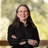 Smiling woman in black shirt, arms crossed.